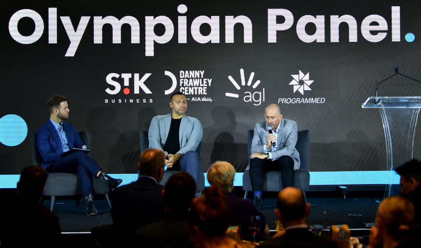Hunter facilitating an Olympian panel conversation on stage in front of an audience
