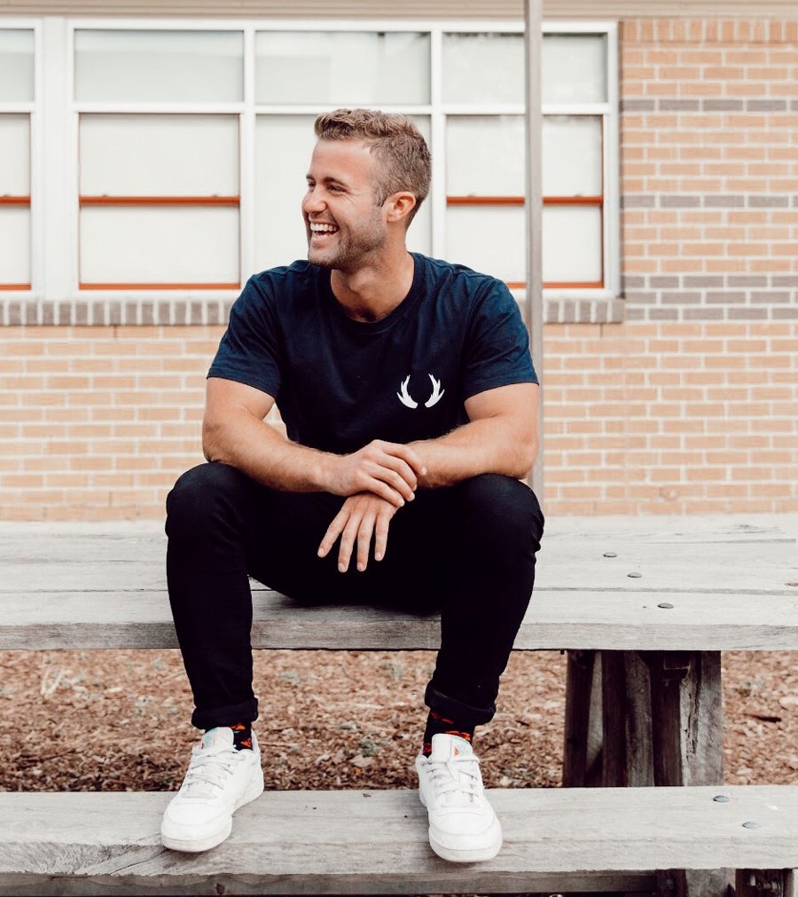 Hunter laughing, sitting on timber seating outside a brick building